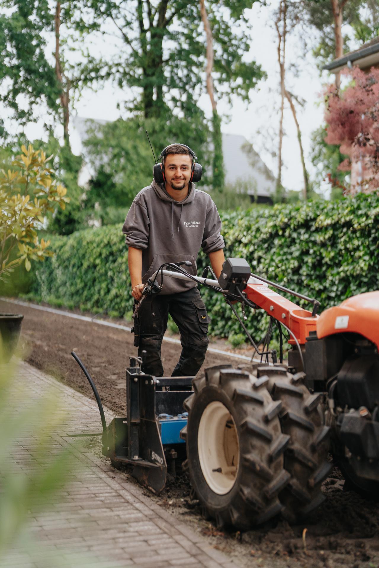 Vakman freest de ondergrond voor de aanleg van een nieuwe tuin.