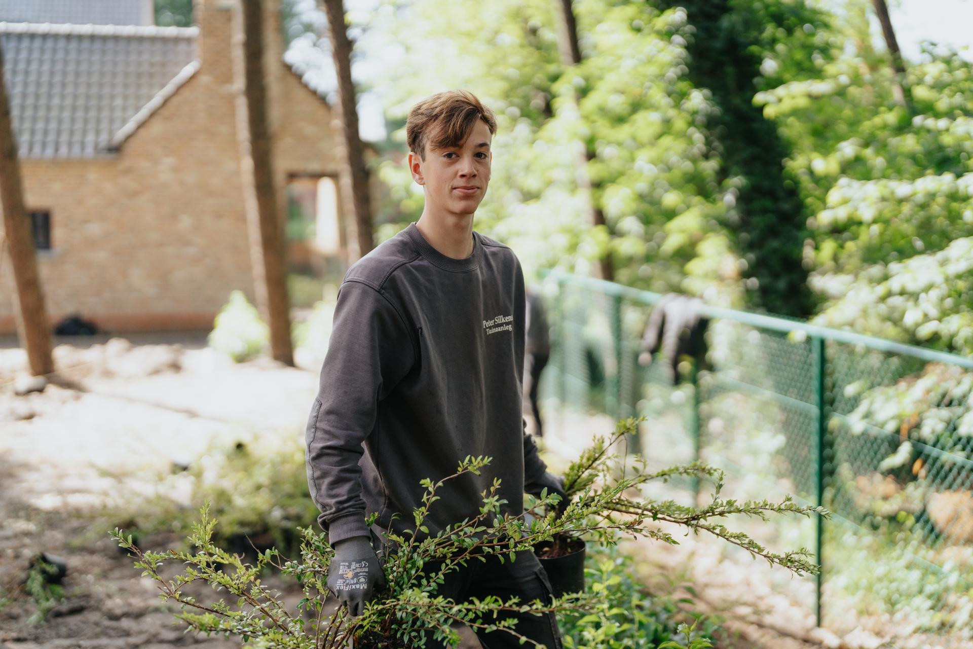 Tuinmedewerker plant heesters aan tijdens een tuinproject.